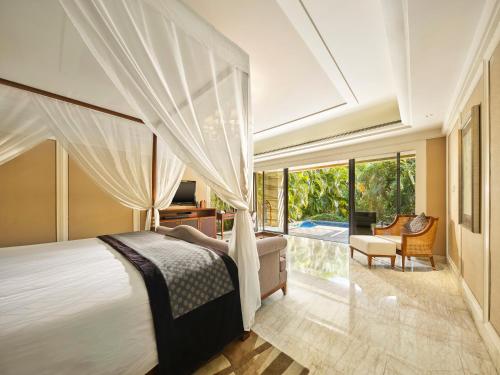 a master bedroom with a bed and a balcony at Wanda Reign Resort & Villas Sanya Haitang Bay in Sanya