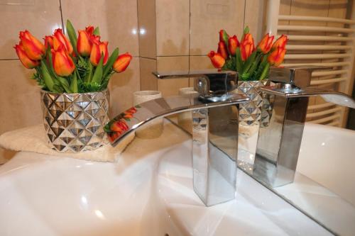 un lavabo con 2 jarrones de tulipanes rojos en APARTMENT MARKO, en Senj