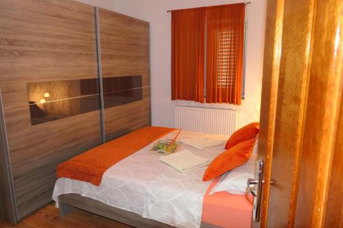 Dormitorio pequeño con cama con almohadas de color naranja en APARTMENT MARKO, en Senj
