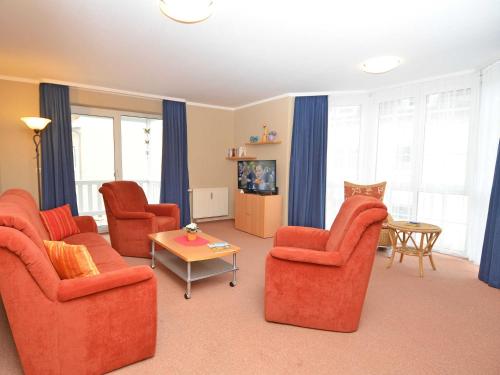 a living room with orange chairs and a table at Ferienwohnungen Schulte in Baabe