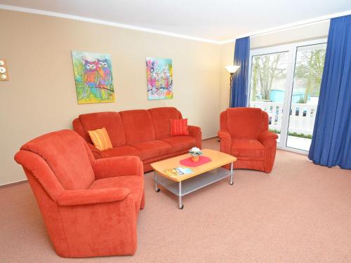 Sala de estar con 2 sillas de color naranja y mesa en Ferienwohnungen Schulte en Baabe