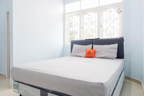Una cama con una almohada naranja encima. en KoolKost Syariah near Green Pramuka Square Mall - Minimal Stay 6 Nights en Yakarta