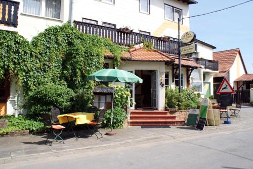 a table with an umbrella in front of a building at Gasthaus Pension Schumbert in Bullau