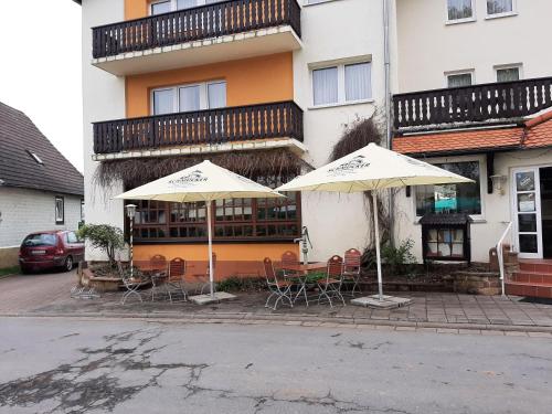 two tables and chairs with umbrellas in front of a building at Gasthaus Pension Schumbert in Bullau