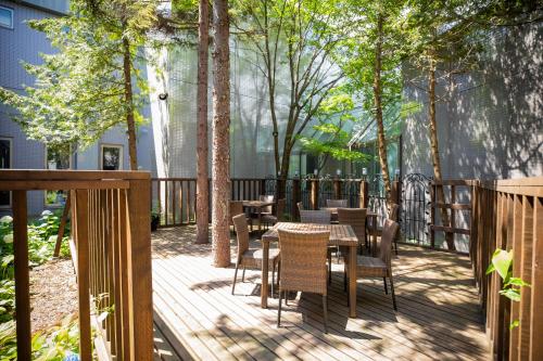 una terrazza in legno con tavoli, sedie e alberi di Otaru Asari Classe Hotel a Otaru