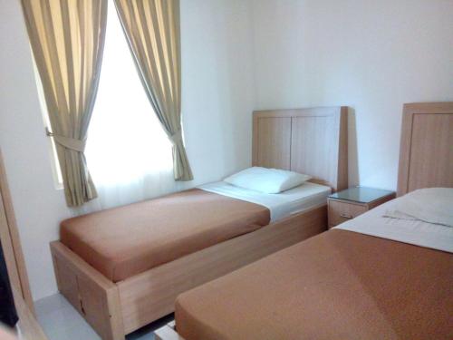 ein kleines Schlafzimmer mit 2 Betten und einem Fenster in der Unterkunft The Abidin Hotel Syari'ah in Padang
