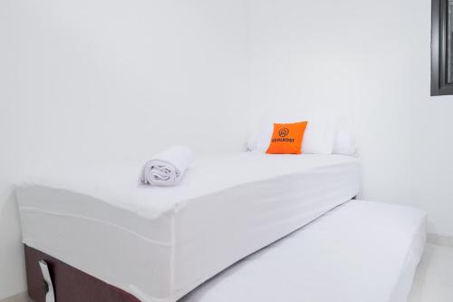 ein weißes Bett mit orangefarbenem Kissen darauf in der Unterkunft KoolKost near Jalan Veteran Raya (Minimum Stay 6 Nights) in Jakarta