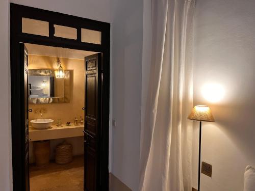 baño con lavabo, espejo y puerta en RIAD ENNAFOURA BOUTIQUE HOTEL en Marrakech