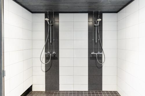 a shower in a bathroom with white tiled walls at Hotel Metsähirvas in Rovaniemi