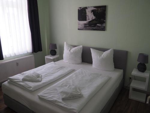 a bedroom with a bed with white sheets and pillows at Askanier in Ballenstedt