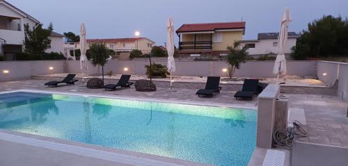 Una piscina con sillas y sombrillas al lado de una casa. en Villa-Sana, en Vir