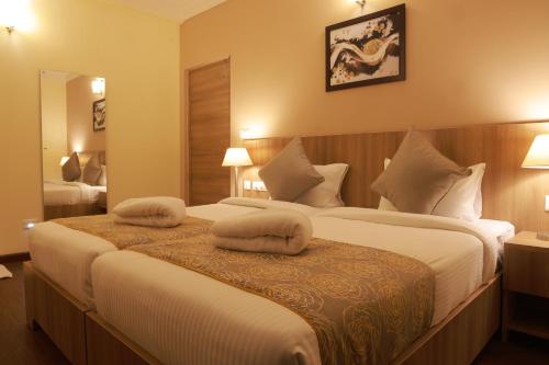 a hotel room with a large bed with two pillows on it at Starlit Suites Tirupati in Tirupati