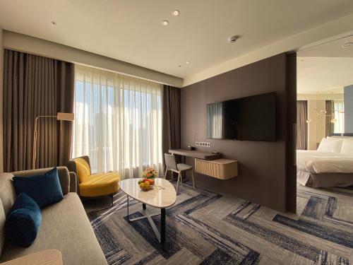 a hotel room with a couch and a bed and a television at Monarch Plaza Hotel in Taoyuan