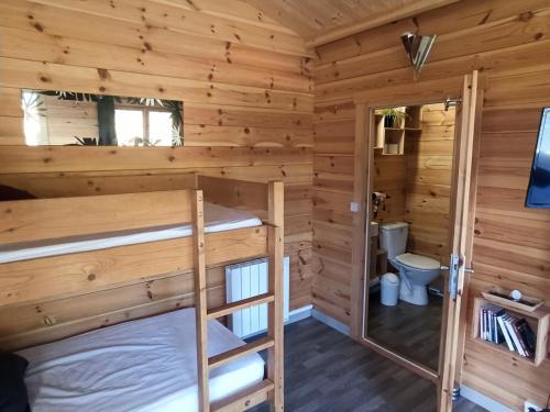 a cabin with two bunk beds and a toilet at Gîte Les chalets du Fliers Location de vacances à la Mer - en Chalets BERCK SUR MER in Verton
