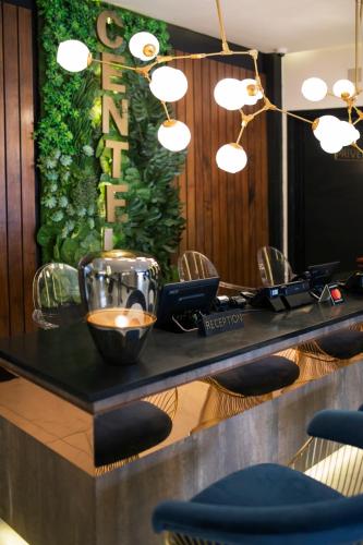 a bar with a green wall with lights and chairs at Le Centell Hotel & Spa in Antananarivo