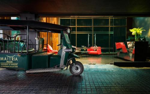 a green scooter parked in a room with a building at Maitria Mode Sukhumvit 15 Bangkok - A Chatrium Collection in Bangkok