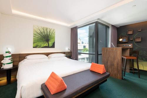 a bedroom with a large bed with orange pillows at Maitria Mode Sukhumvit 15 Bangkok - A Chatrium Collection in Bangkok