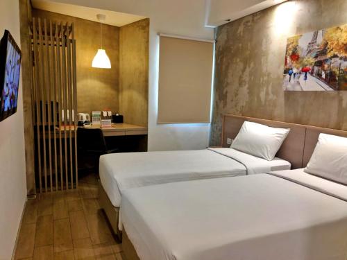 a hotel room with two beds and a desk at Swiss-Belexpress Cilegon in Cilegon