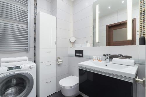 a white bathroom with a washing machine and a sink at Kraków Błonia Apartment with Balcony by Renters in Kraków