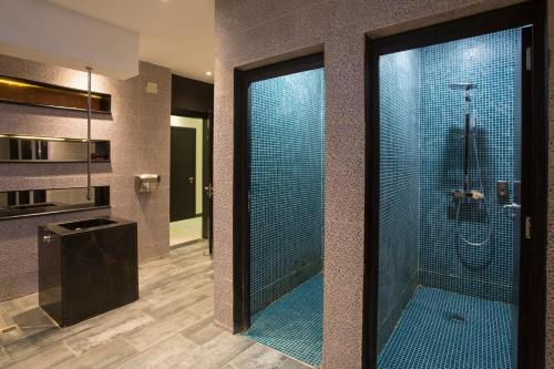 a bathroom with a glass shower with blue tiles at Le Centell Hotel & Spa in Antananarivo