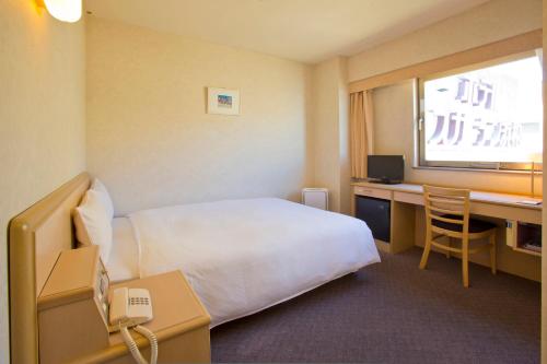 a hotel room with a bed and a desk and a window at Hotel South Garden Hamamatsu in Hamamatsu
