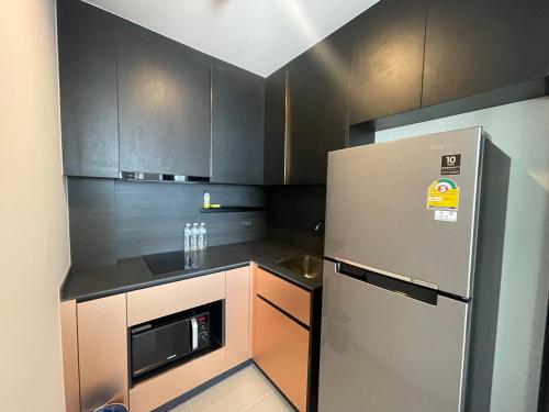 a kitchen with black cabinets and a stainless steel refrigerator at The Edge central pattaya in Pattaya Central