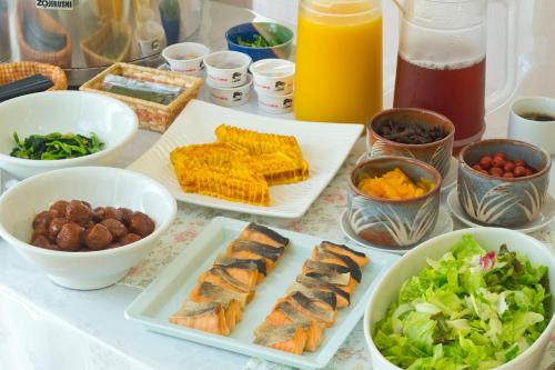 a table with plates of food and bowls of vegetables at Hotel South Garden Hamamatsu in Hamamatsu