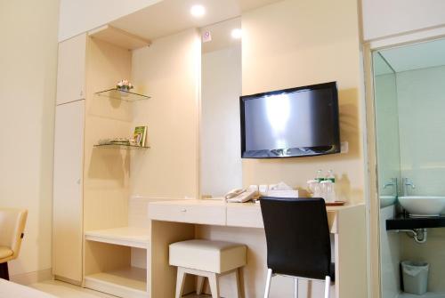 een kamer met een bureau en een tv aan de muur bij The Sriwijaya Hotel - Halal Hotel in Padang