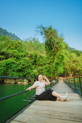 a woman is sitting on a wooden bridge at Ba Bể Green (View Ba Be lake) in Bak Kan