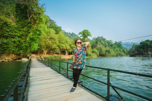 a woman is standing on a bridge over a river at Ba Bể Green (View Ba Be lake) in Bak Kan