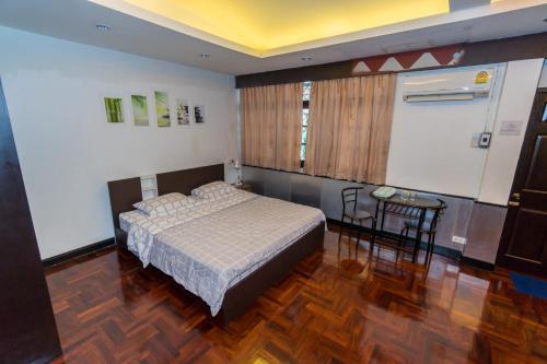 Schlafzimmer mit einem Bett und einem Tisch in der Unterkunft Flourish Apartments in Bangkok