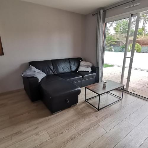un salon avec un canapé en cuir noir et une table dans l'établissement Appartement dans habitation privée avec piscine, à La Milesse
