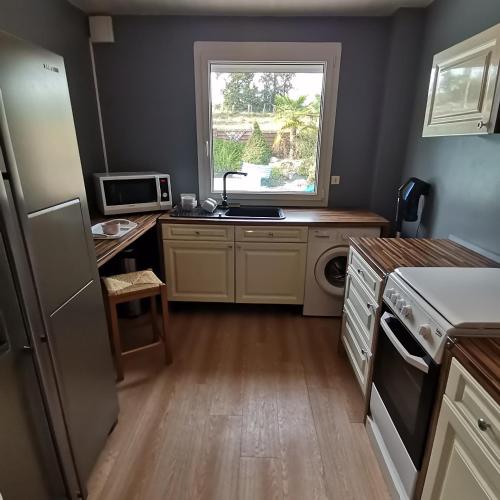 Il comprend une cuisine équipée d'un réfrigérateur, d'un évier et d'une fenêtre. dans l'établissement Appartement dans habitation privée avec piscine, à La Milesse