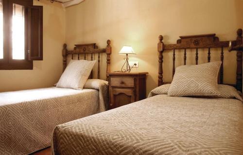 a bedroom with two beds and a lamp and a window at Casa Rural Fuente Zagrilla in Zagrilla