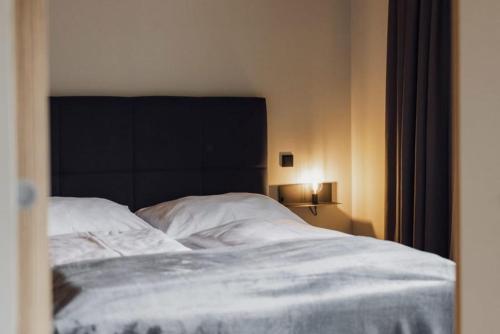 a bed with white sheets and a black headboard at Blue Note Apartments in Schoppernau