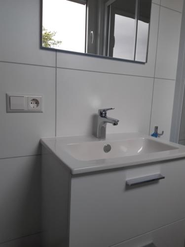een witte badkamer met een wastafel en een spiegel bij Merel in Serooskerke
