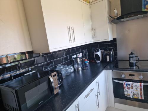 a kitchen with white cabinets and a black microwave at Quin homes in Birmingham