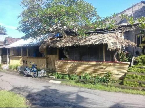 une maison avec un toit en paille et une moto garée devant elle dans l'établissement Bali Livin,tayehomestay, à Banjarangkan