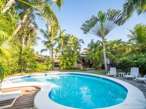 a pool with chairs and palm trees in front of a house at Résidence Villas Les Hibiscus in Las Terrenas