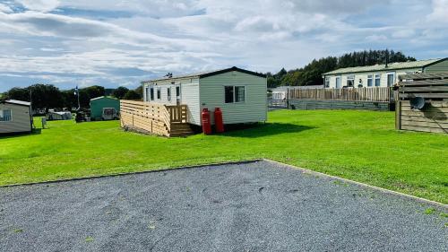 a yard with a shed and a house and grass at TL083 - 2 Bedrooms indoor pool Loch Views fishing Golf Riding Shooting Water Sports 15 min drive to beaches PASSES NOT INCLUDED Most Activities Will Not Be Available Out Of Season Please Check Before Booking in Newton Stewart