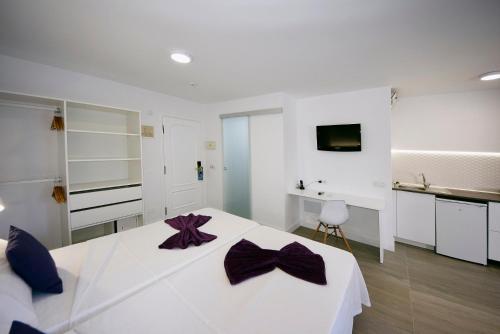 a white bedroom with a large white bed with purple bows at Tenerife Ving in Puerto de la Cruz