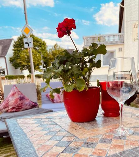 une fleur rouge dans un vase sur une table avec un verre dans l'établissement Ferienhaus Griede, à Mörsdorf