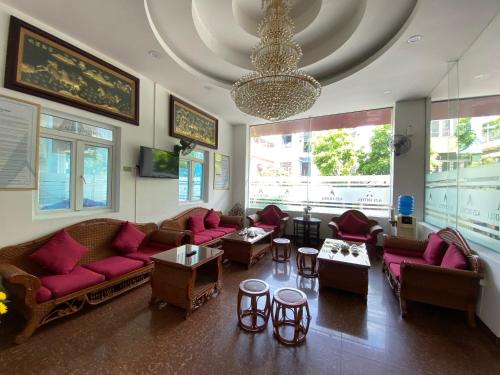 una sala de estar con sofás, mesas y una lámpara de araña. en A25 Hotel -137 Nguyễn Du - Đà Nẵng, en Da Nang