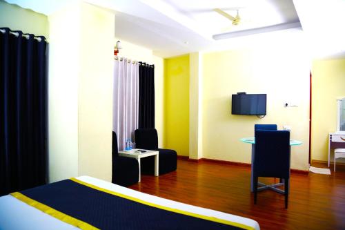a room with a bed and a table and a tv at Green Park Residency in Kannur