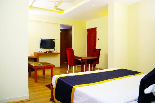 a hotel room with a bed and a desk and a television at Green Park Residency in Kannur