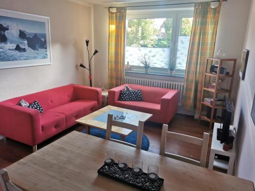 una sala de estar con 2 sofás rojos y una mesa. en Gemütliche Gästewohnung in ruhiger Lage en Kronshagen