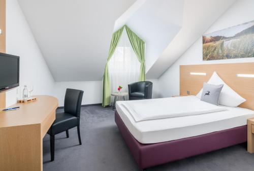 a bedroom with a bed and a desk and a tv at Arberland Tagungshaus in Regen