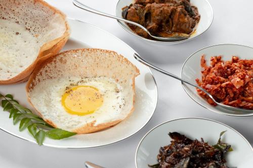 a table with plates of food with an egg and toast at The Albatross, Kandy in Digana