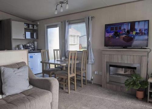ein Wohnzimmer mit einem Sofa, einem Tisch und einem TV in der Unterkunft Immaculate Sen friendly 3-Bed caravan in Porthcawl in Porthcawl