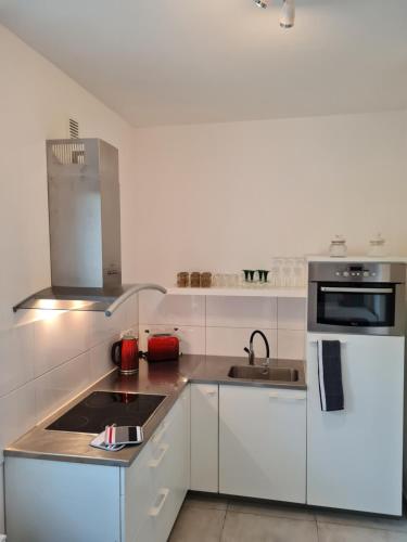 a white kitchen with a sink and a microwave at Ferienwohnung am Kurpark in Bad Rothenfelde